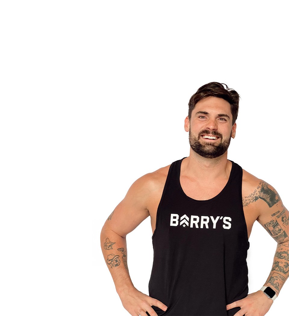 Barry’s instructor wearing a black top standing confidently smiling against a white background