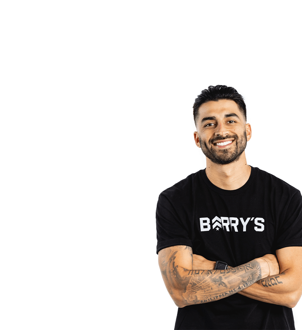 Barry’s instructor wearing a black top standing confidently smiling against a white background
