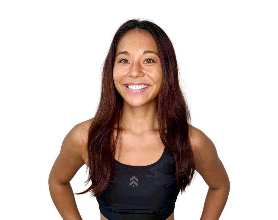 Barry’s instructor wearing a black top standing confidently smiling against a white background