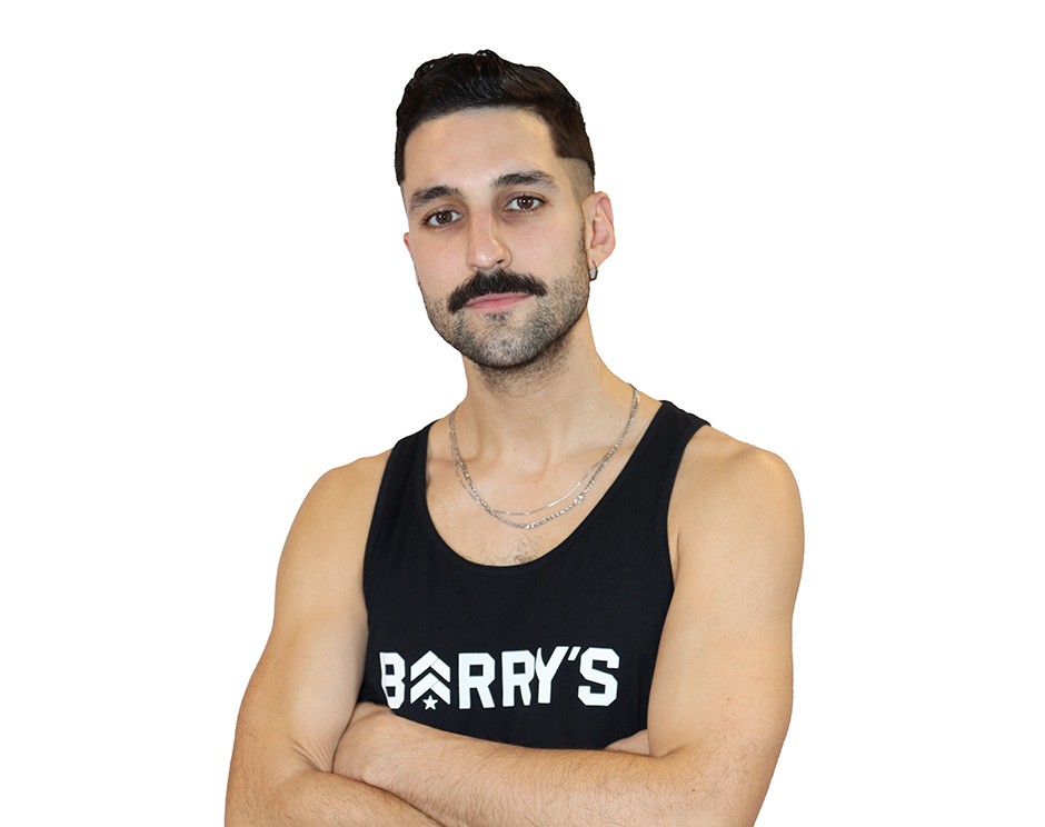 Barry’s instructor wearing a black top standing confidently smiling against a white background