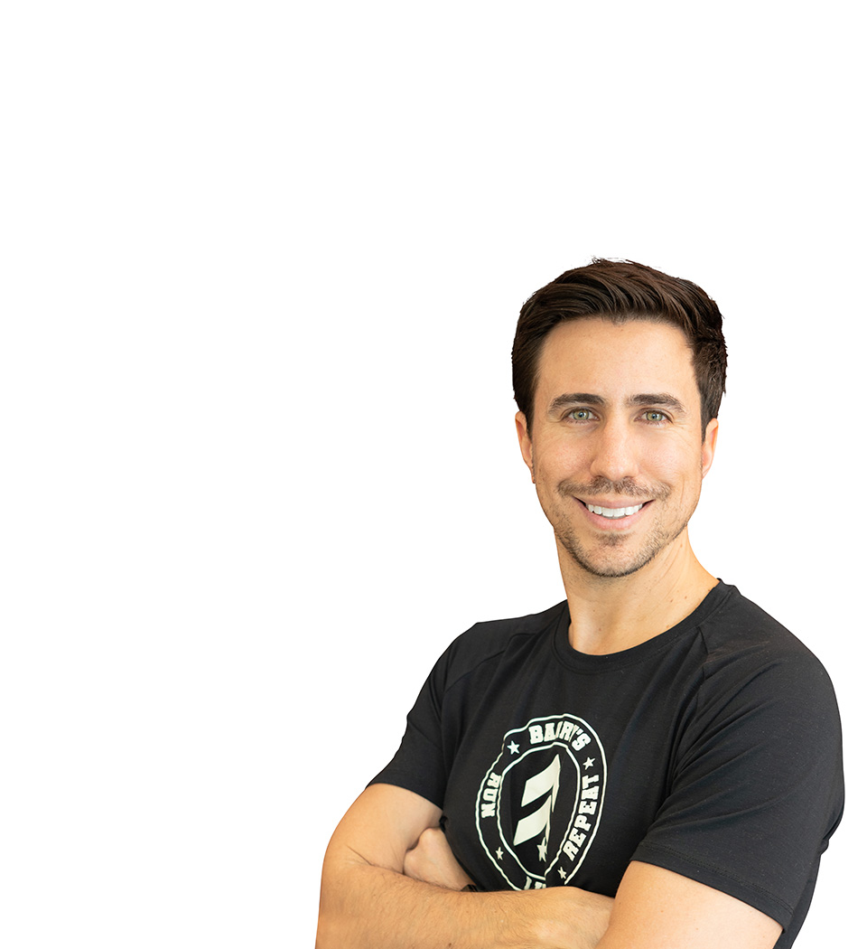 Barry’s instructor wearing a black top standing confidently smiling against a white background