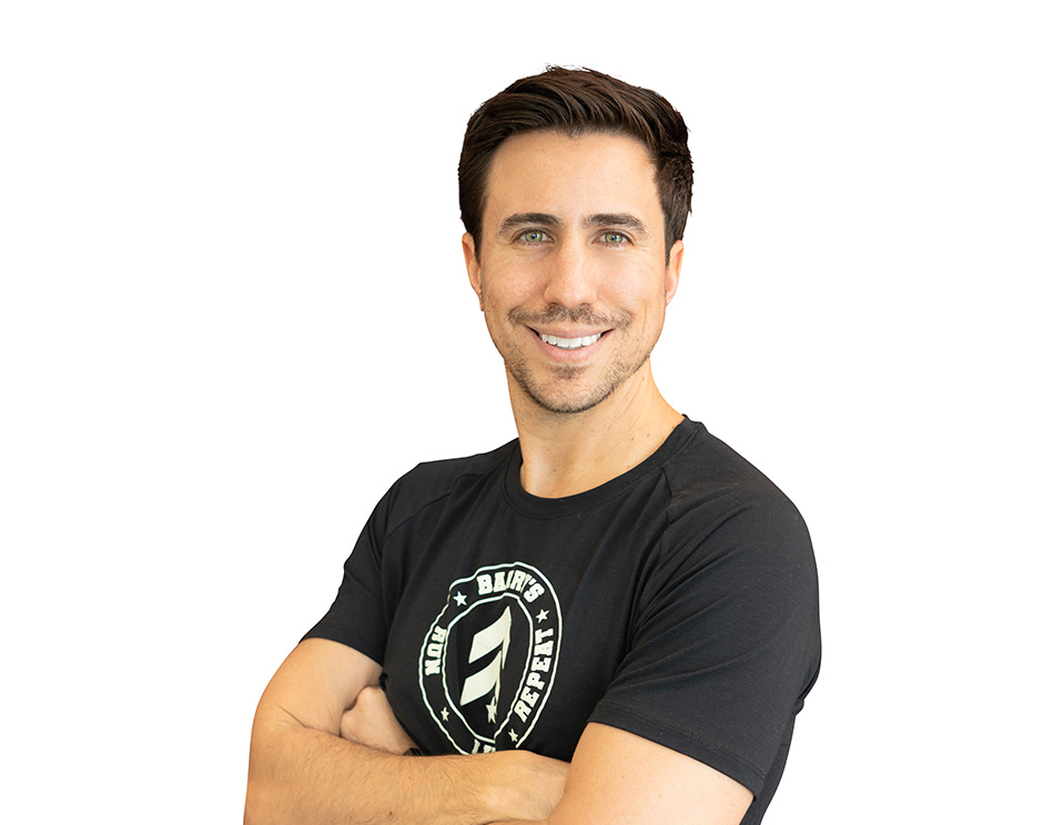 Barry’s instructor wearing a black top standing confidently smiling against a white background