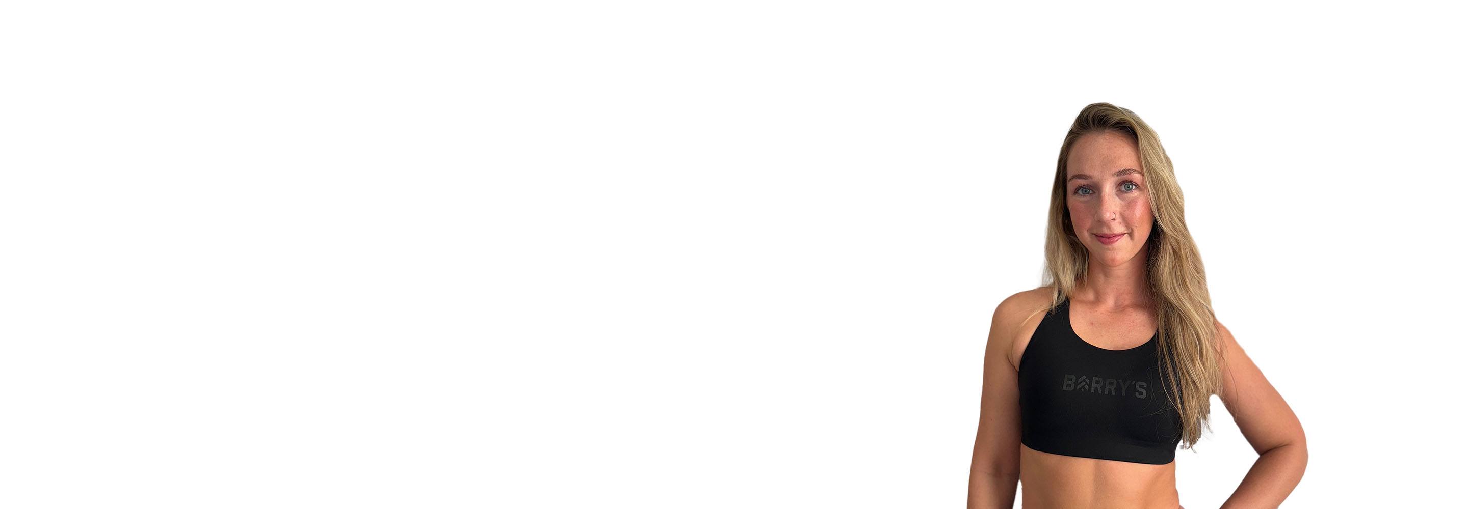 Barry’s instructor wearing a black top standing confidently smiling against a white background
