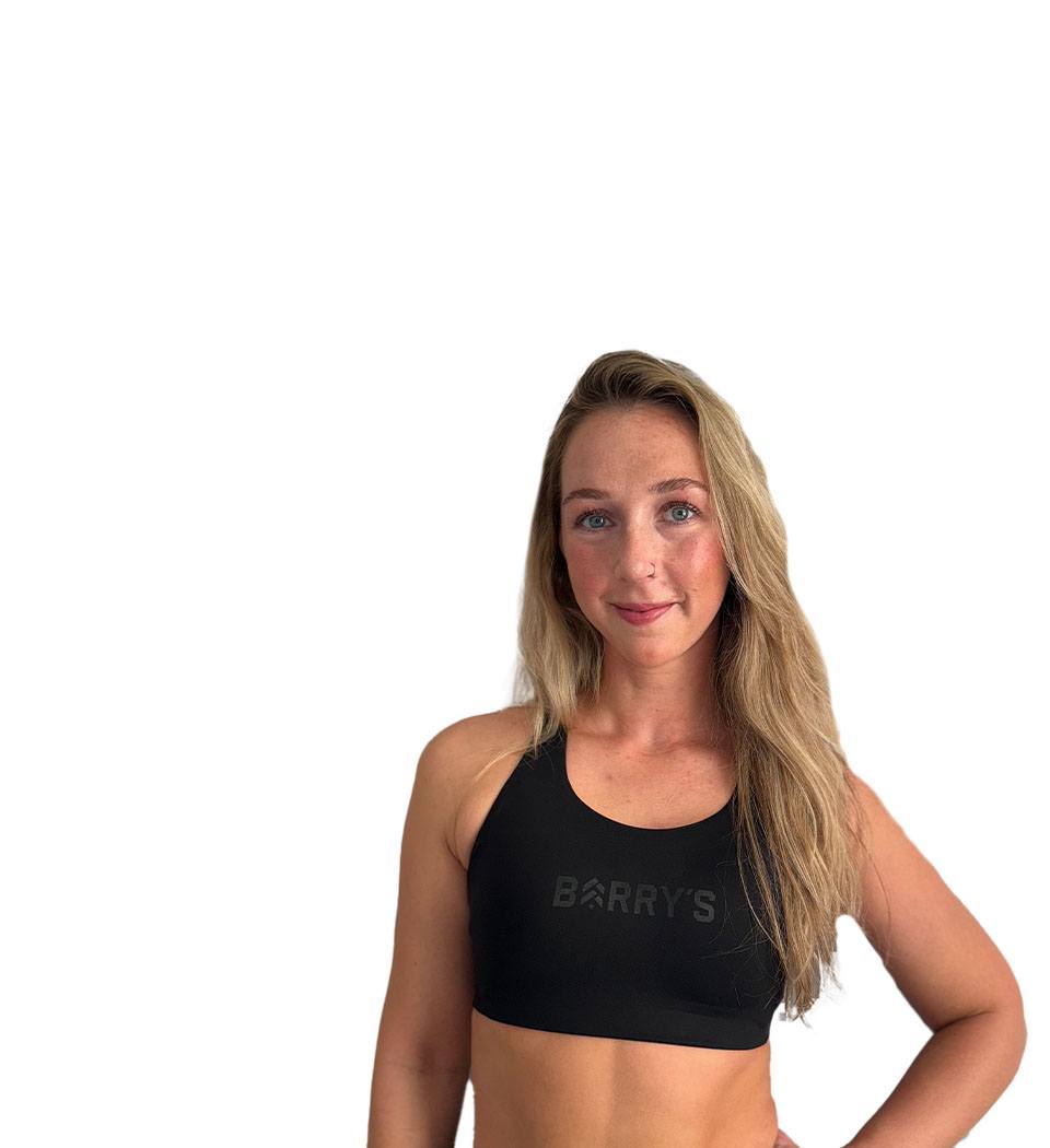 Barry’s instructor wearing a black top standing confidently smiling against a white background