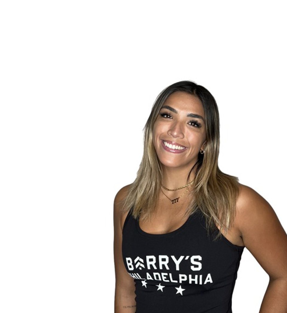 Barry’s instructor wearing a black top standing confidently smiling against a white background