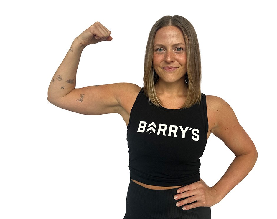 Barry’s instructor wearing a black top standing confidently smiling against a white background