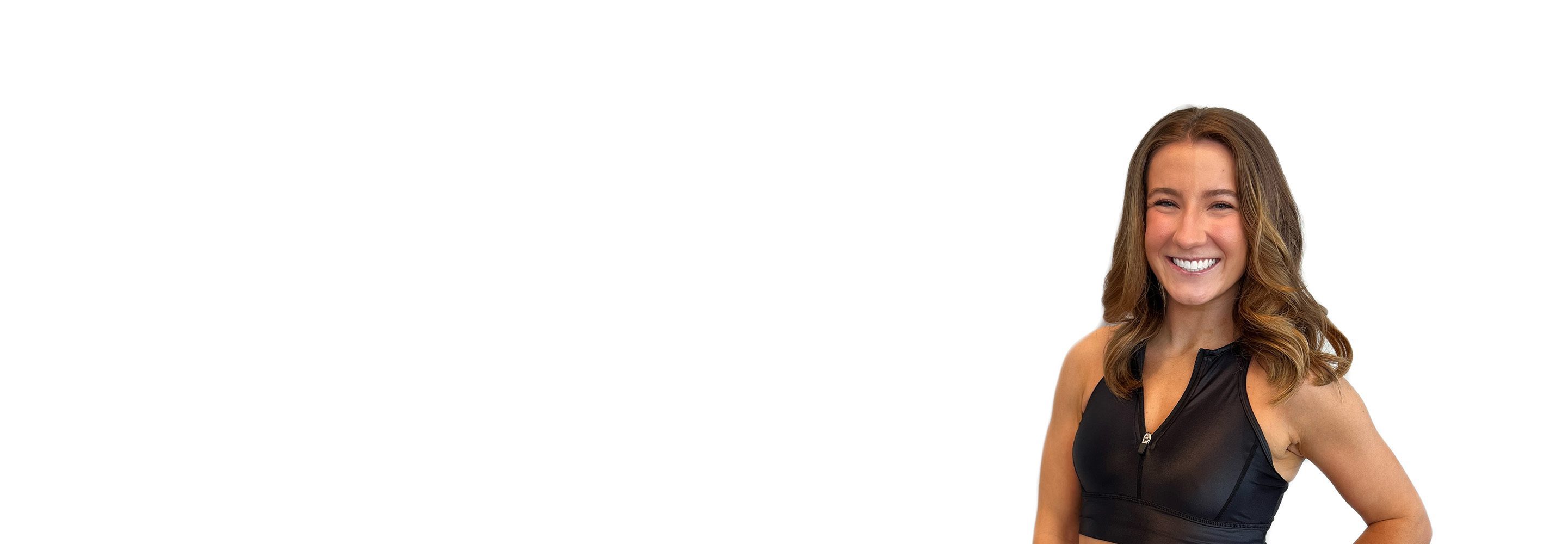 Barry’s instructor wearing a black top standing confidently smiling against a white background