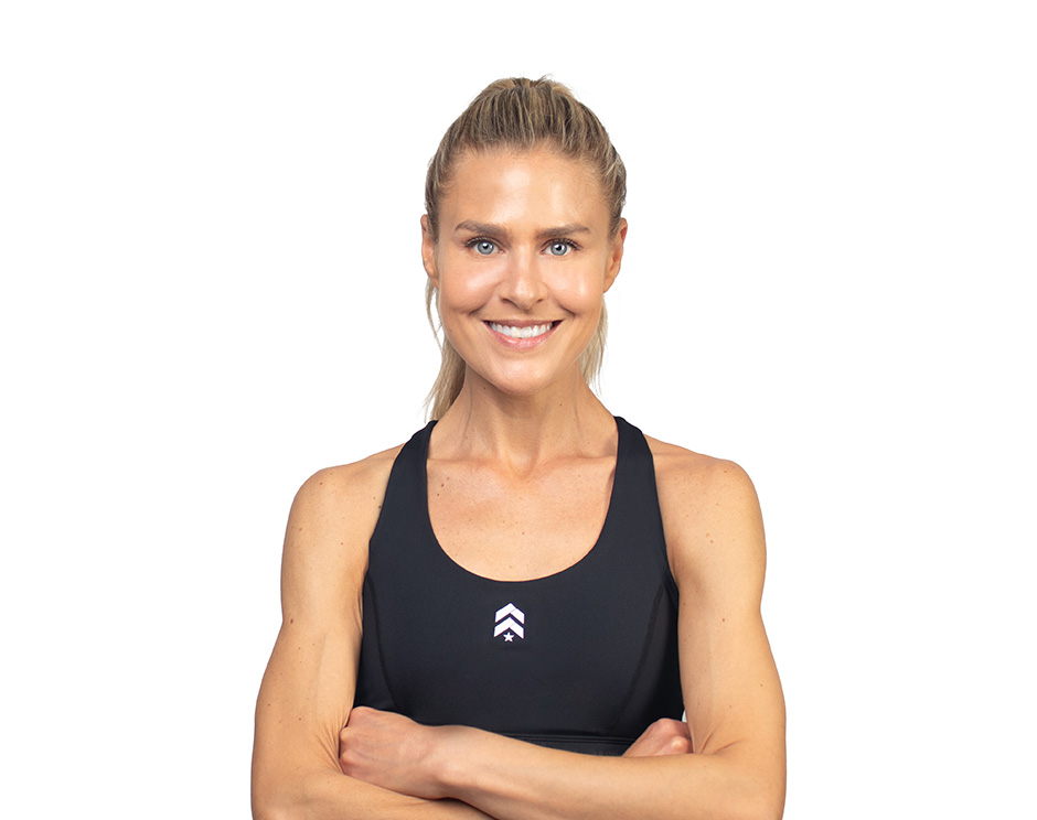 Barry’s instructor wearing a black top standing confidently smiling against a white background