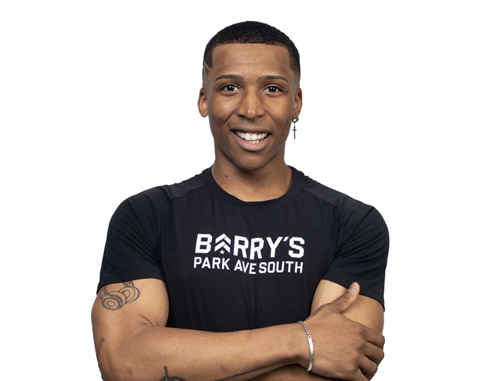 Barry’s instructor wearing a black top standing confidently smiling against a white background