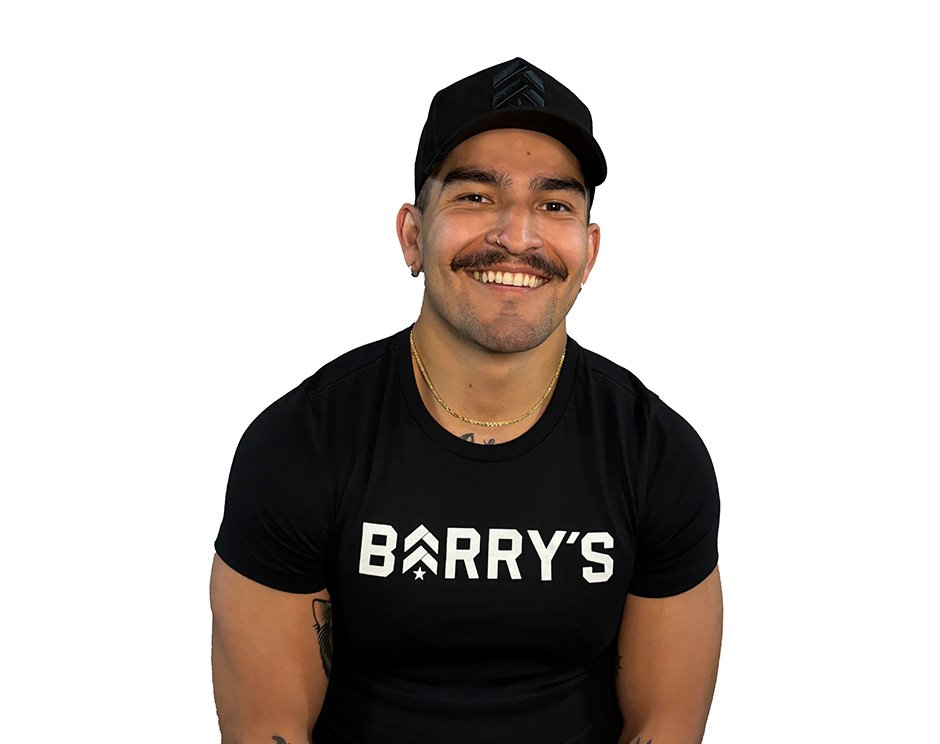 Barry's instructor standing confidently, wearing a black tank top against a white background, ready for the next workout challenge.