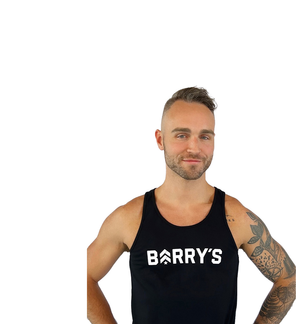 Barry’s instructor wearing a black top standing confidently smiling against a white background
