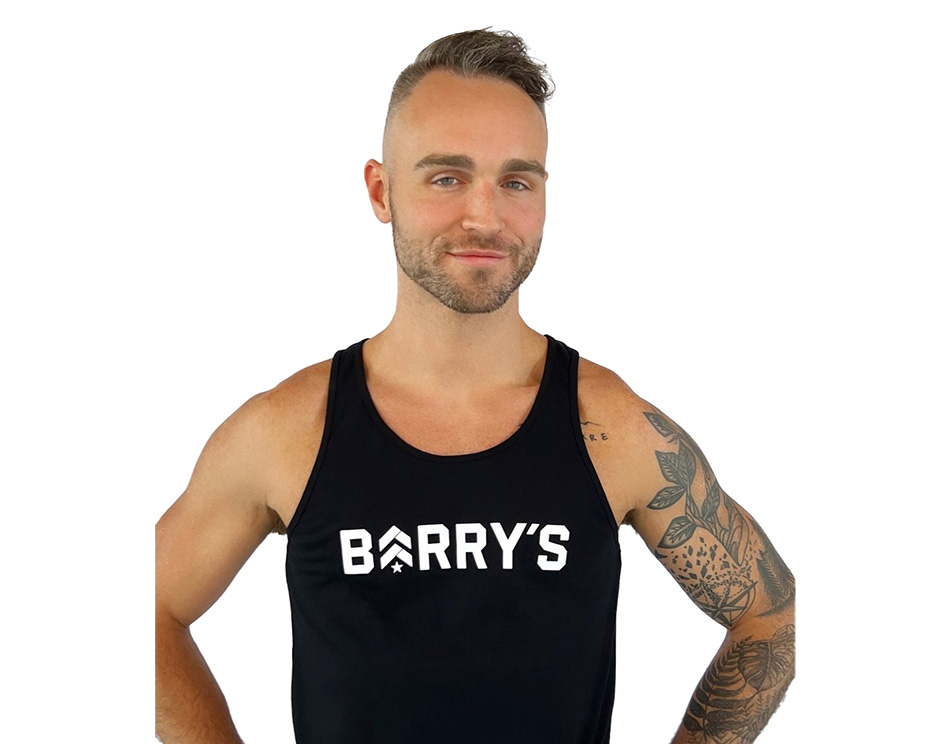 Barry’s instructor wearing a black top standing confidently smiling against a white background