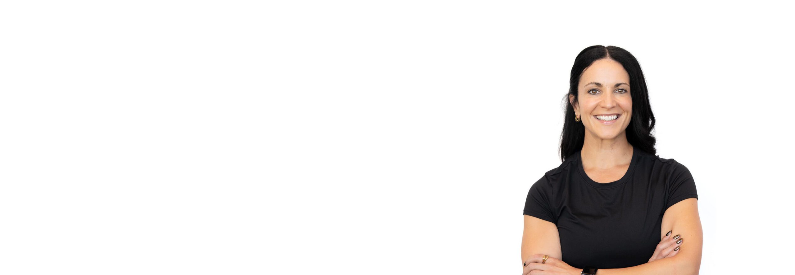 Barry’s instructor wearing a black top standing confidently smiling against a white background