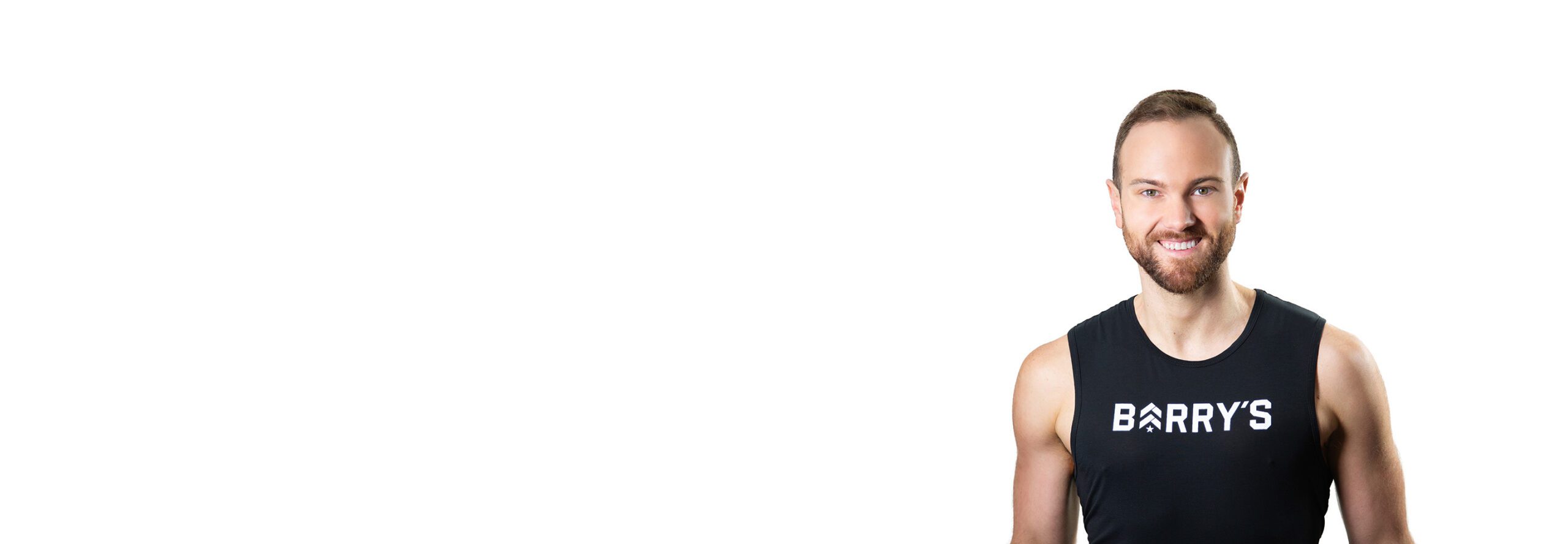 Barry’s instructor wearing a black top standing confidently smiling against a white background