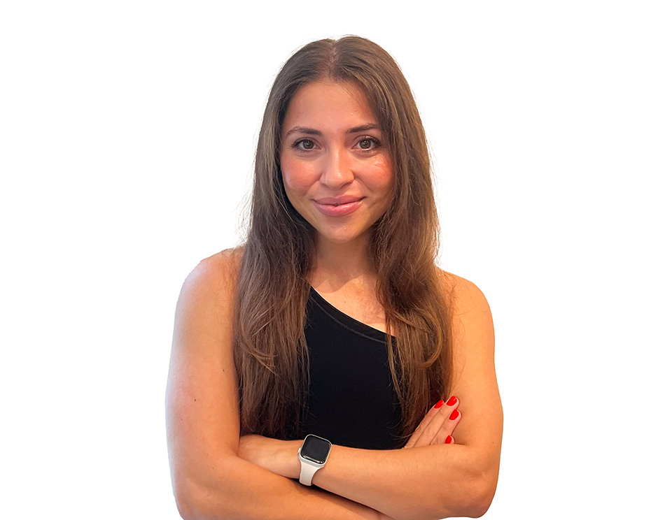 Barry's instructor standing confidently with arms crossed in front, wearing a black tank top against a white background, ready for the next workout challenge.