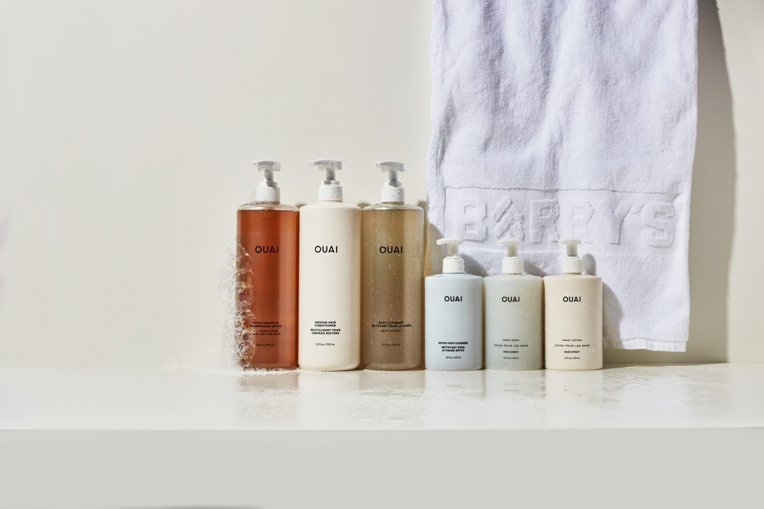 ouai hair and body products displayed in front of a white Barry's towel