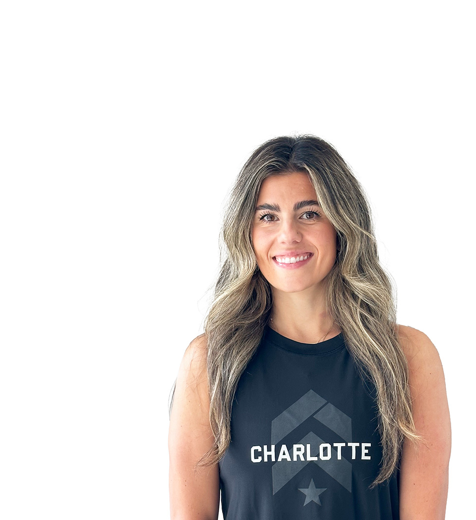 Barry’s instructor wearing a black top standing confidently smiling against a white background