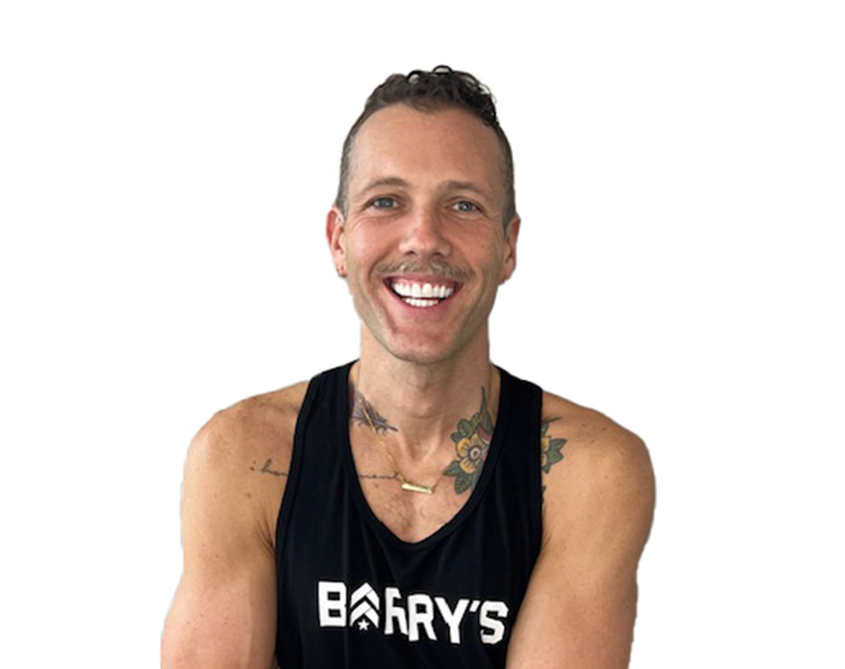 Barry’s instructor wearing a black top standing confidently smiling against a white background