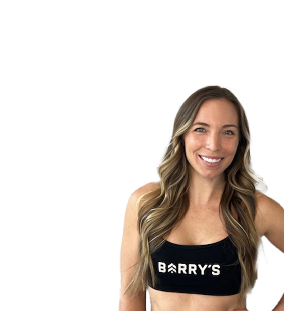 Barry’s instructor wearing a black top standing confidently smiling against a white background