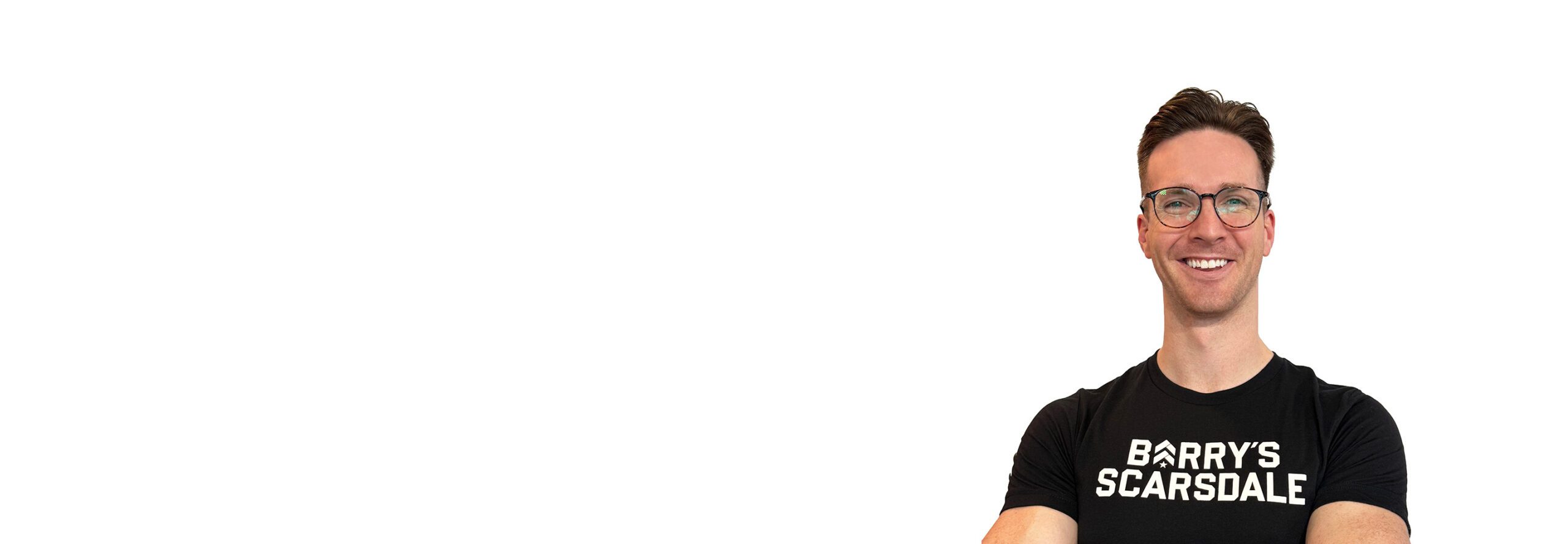 Barry’s instructor wearing a black top standing confidently smiling against a white background