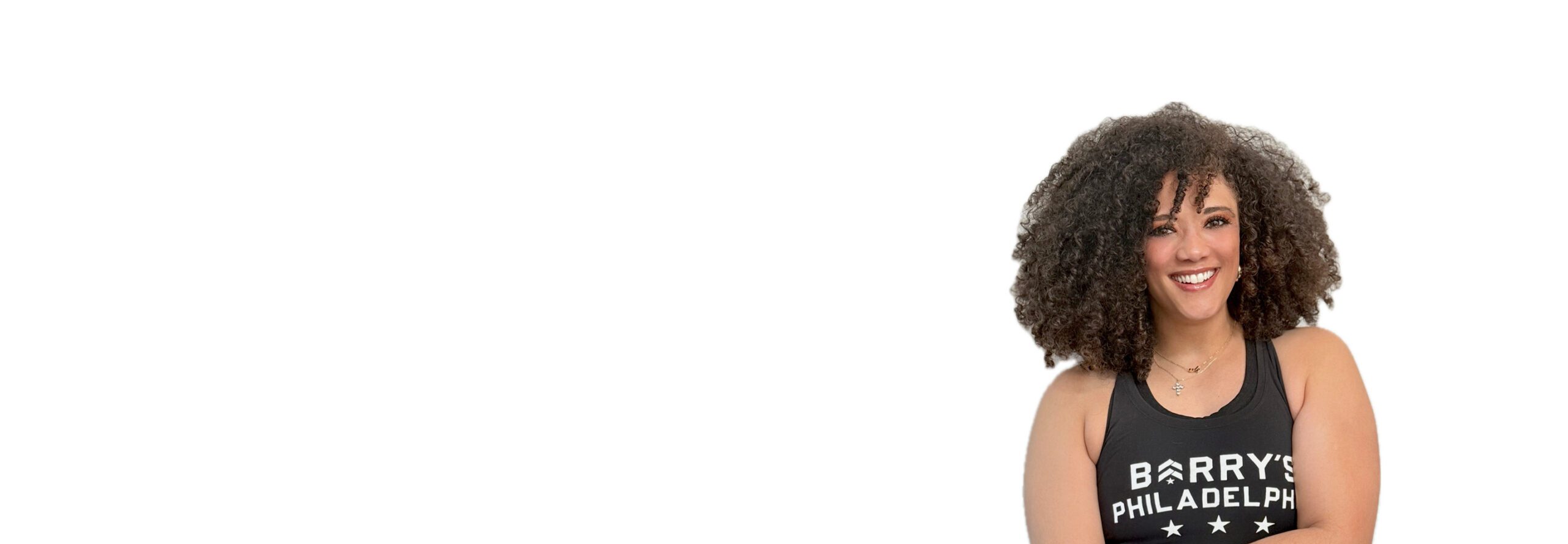 Barry’s instructor wearing a black top standing confidently smiling against a white background