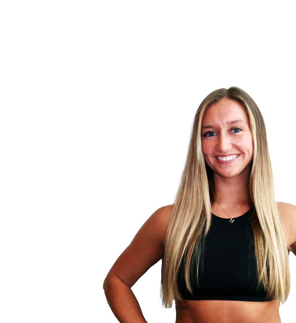 Barry’s instructor wearing a black top standing confidently smiling against a white background