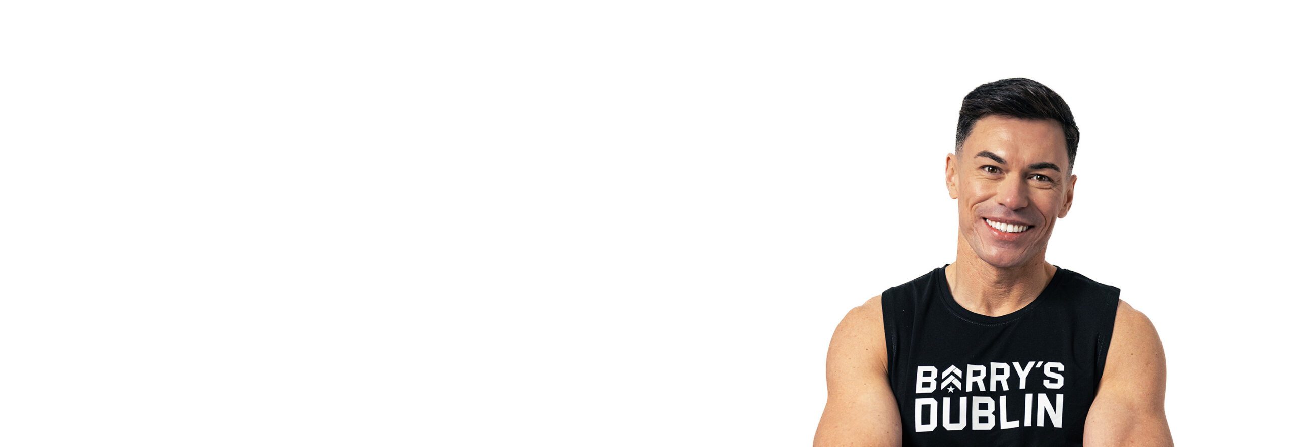 Barry’s instructor wearing a black top standing confidently smiling against a white background