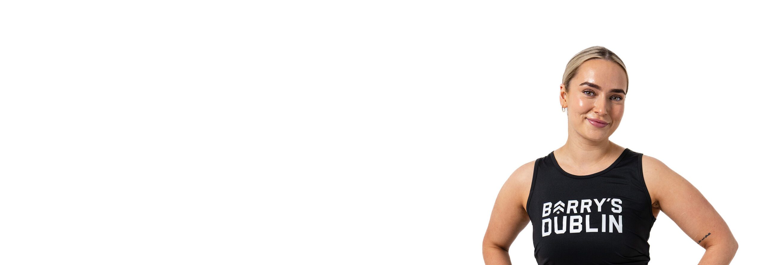 Barry’s instructor wearing a black top standing confidently smiling against a white background