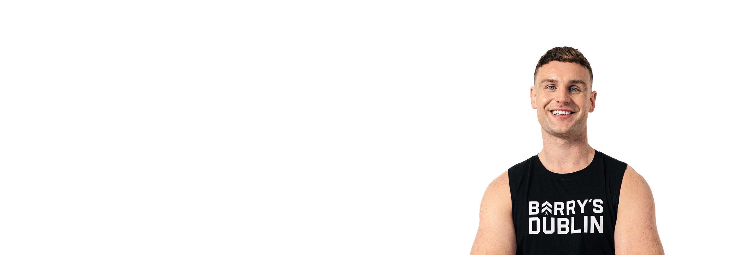 Barry’s instructor wearing a black top standing confidently smiling against a white background
