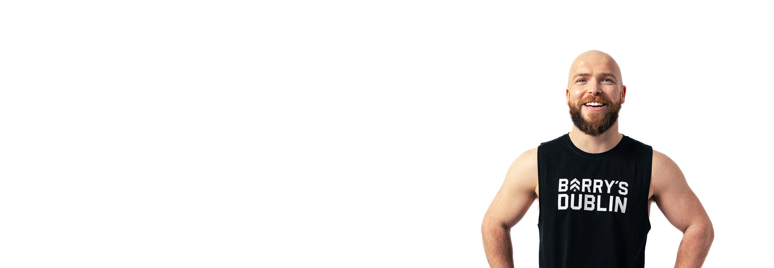 Barry’s instructor wearing a black top standing confidently smiling against a white background