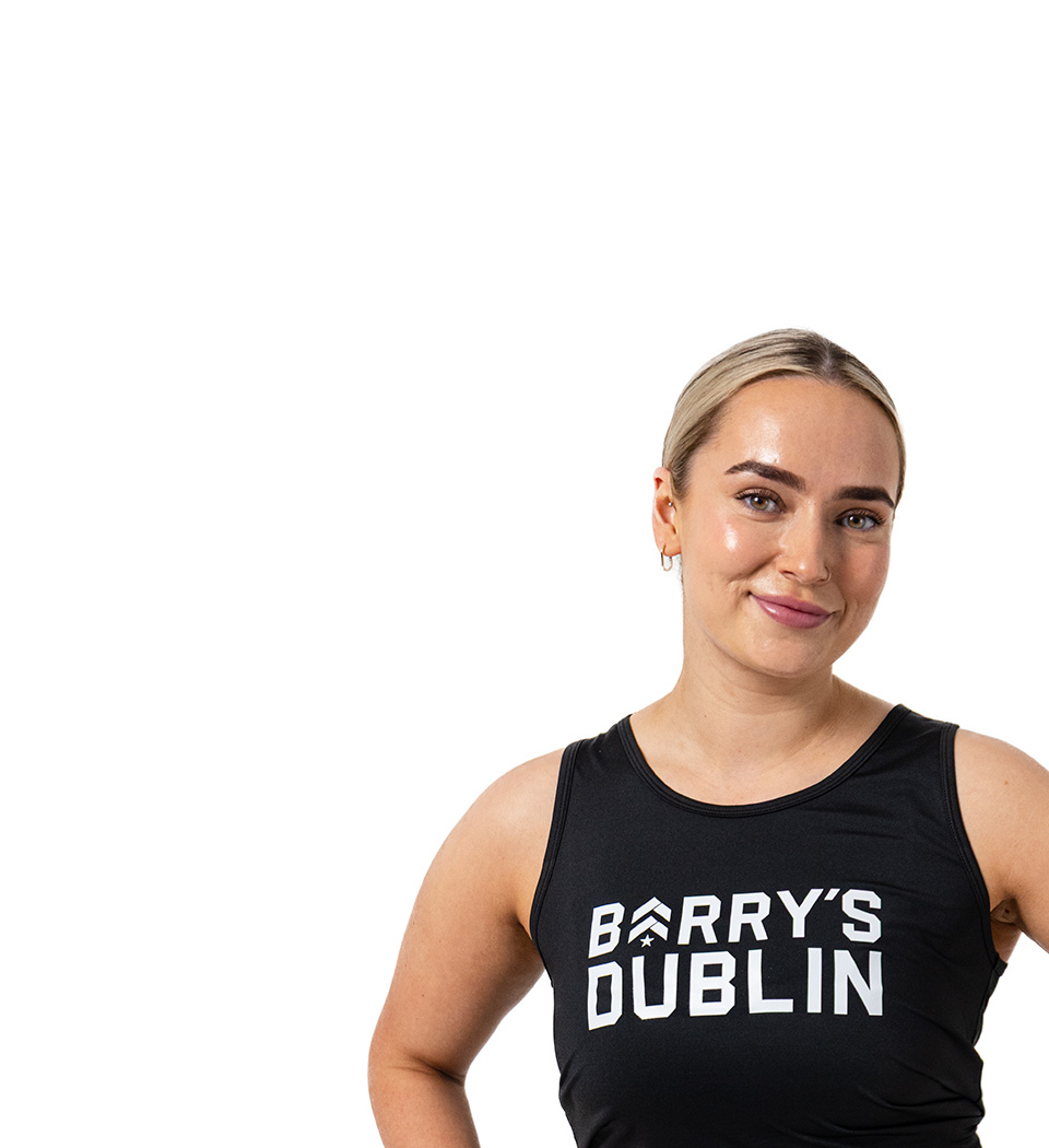 Barry’s instructor wearing a black top standing confidently smiling against a white background