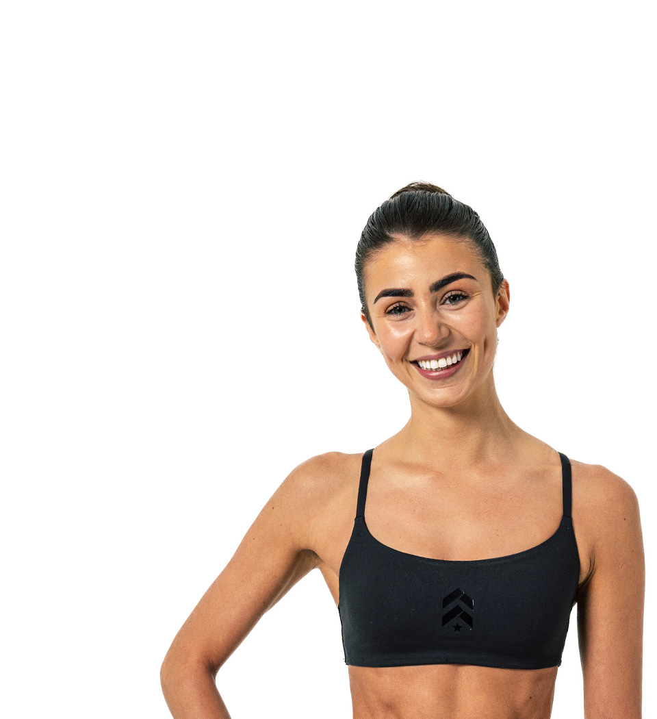 Barry’s instructor wearing a black top standing confidently smiling against a white background