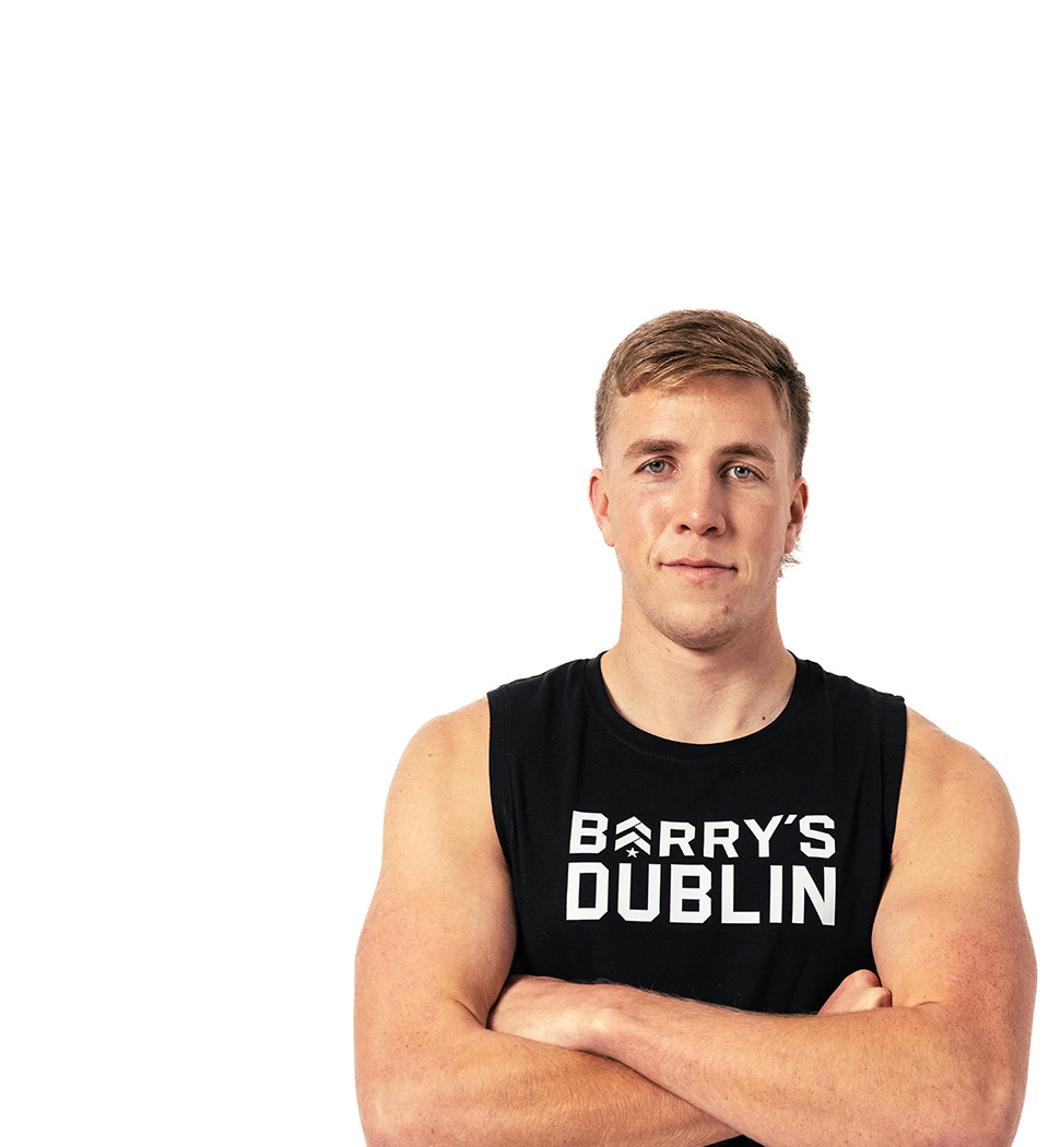 Barry’s instructor wearing a black top standing confidently smiling against a white background