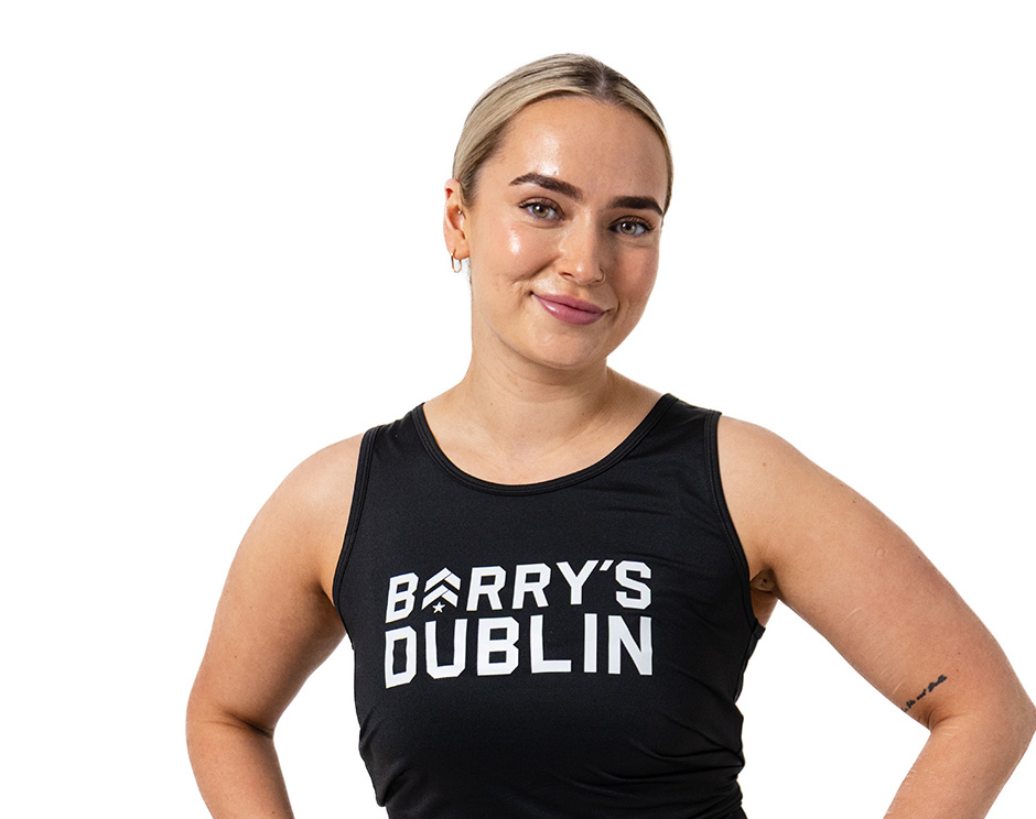 Barry’s instructor wearing a black top standing confidently smiling against a white background