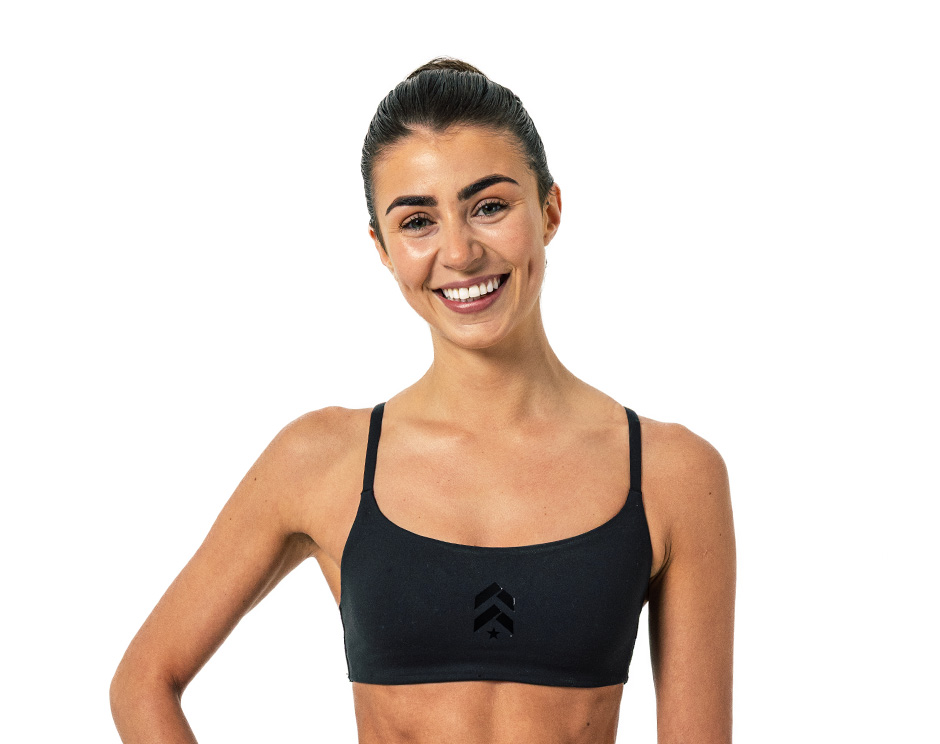 Barry’s instructor wearing a black top standing confidently smiling against a white background