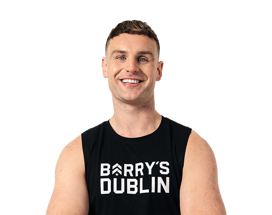 Barry’s instructor wearing a black top standing confidently smiling against a white background