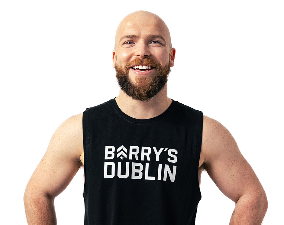 Barry’s instructor wearing a black top standing confidently smiling against a white background