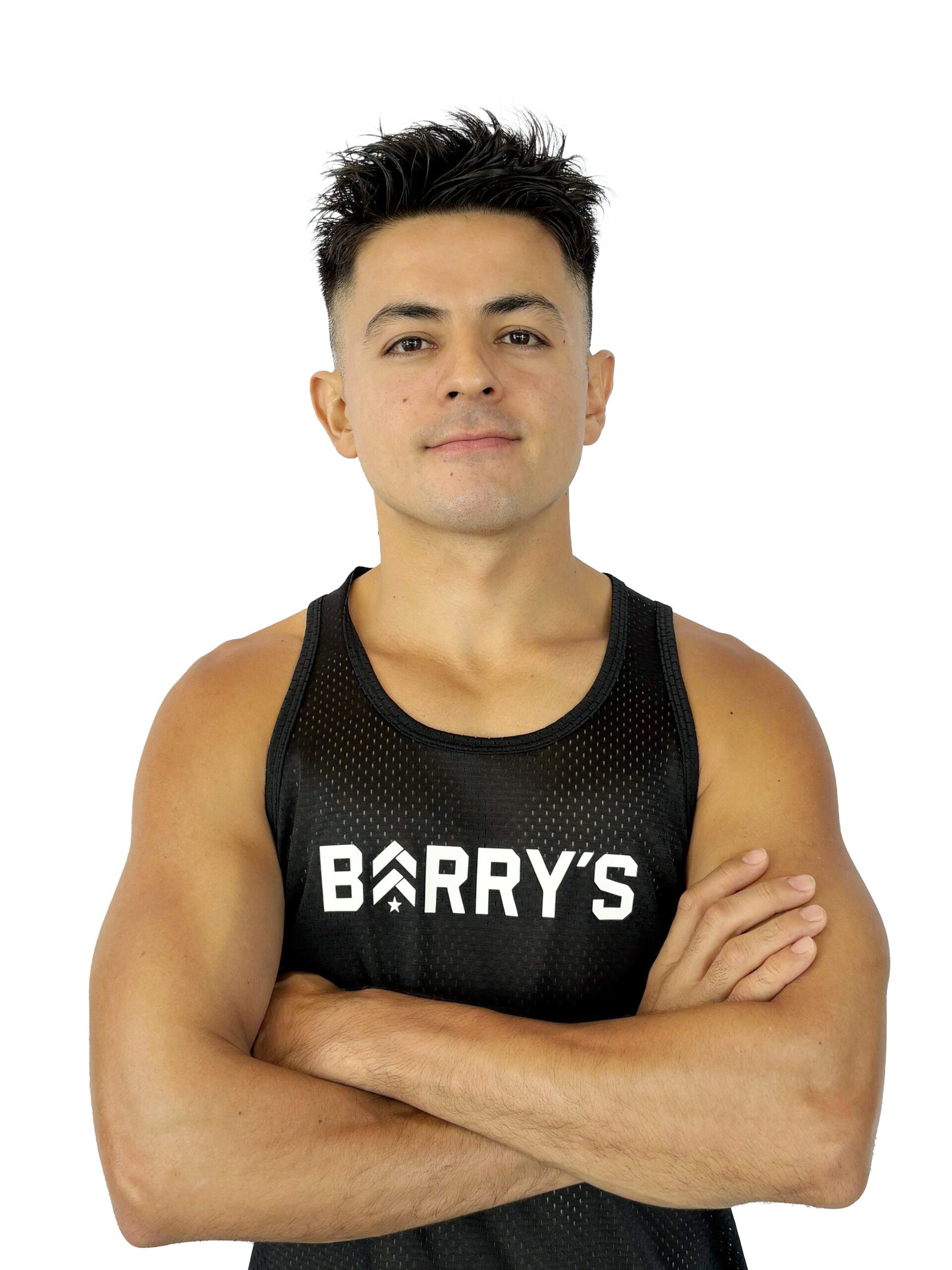 Barry’s instructor wearing a black top standing confidently smiling against a white background