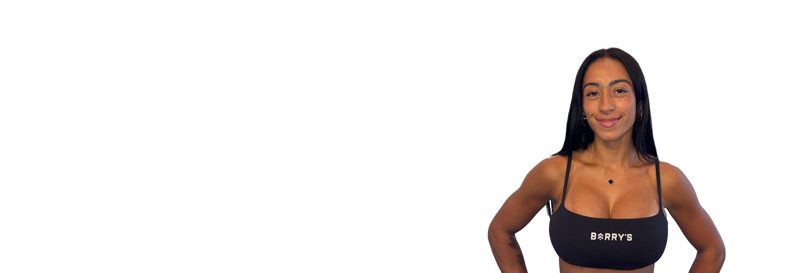 Barry’s instructor wearing a black top standing confidently smiling against a white background