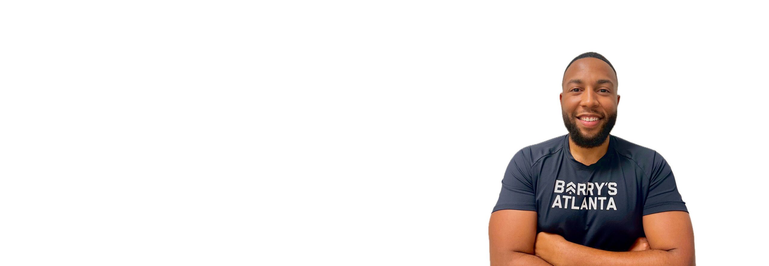 Barry’s instructor wearing a black top standing confidently smiling against a white background