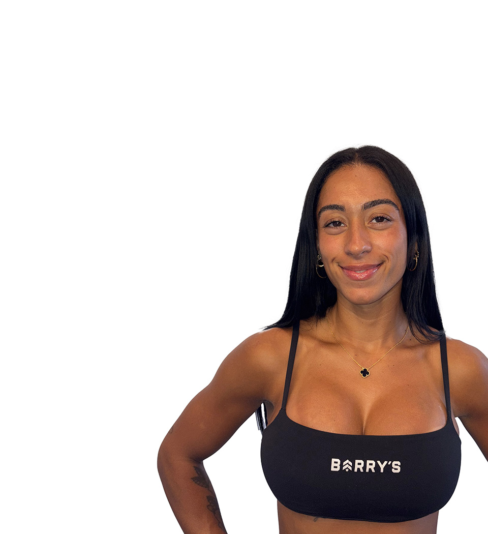 Barry’s instructor wearing a black top standing confidently smiling against a white background