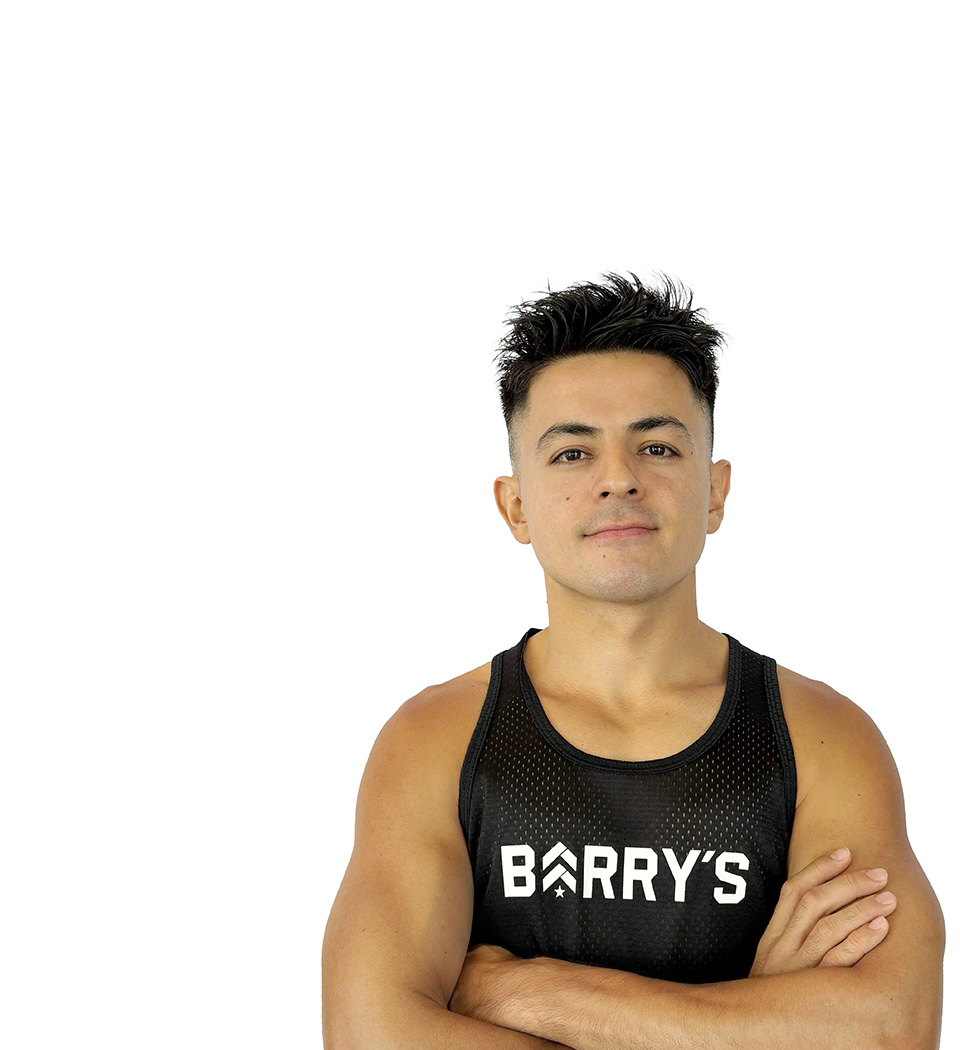 Barry’s instructor wearing a black top standing confidently smiling against a white background