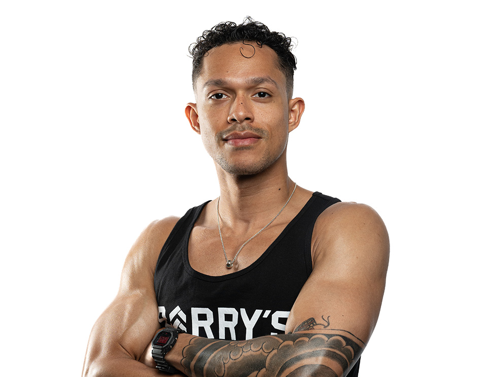 Barry’s instructor wearing a black top standing confidently smiling against a white background