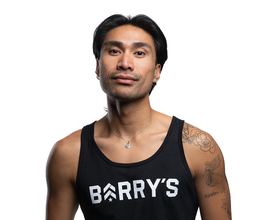 Barry’s instructor wearing a black top standing confidently smiling against a white background