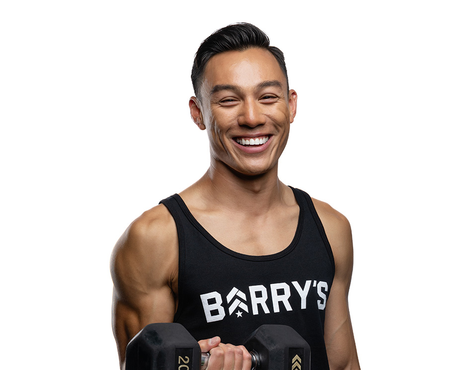 Barry’s instructor wearing a black top standing confidently smiling against a white background