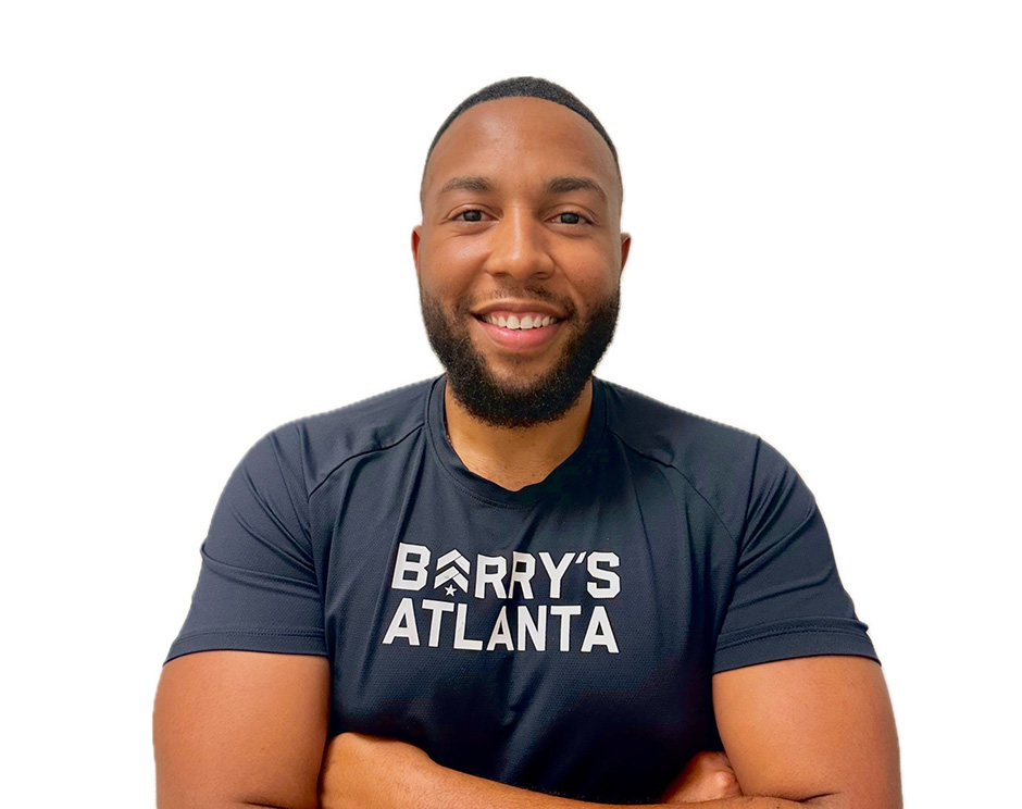 Barry’s instructor wearing a black top standing confidently smiling against a white background